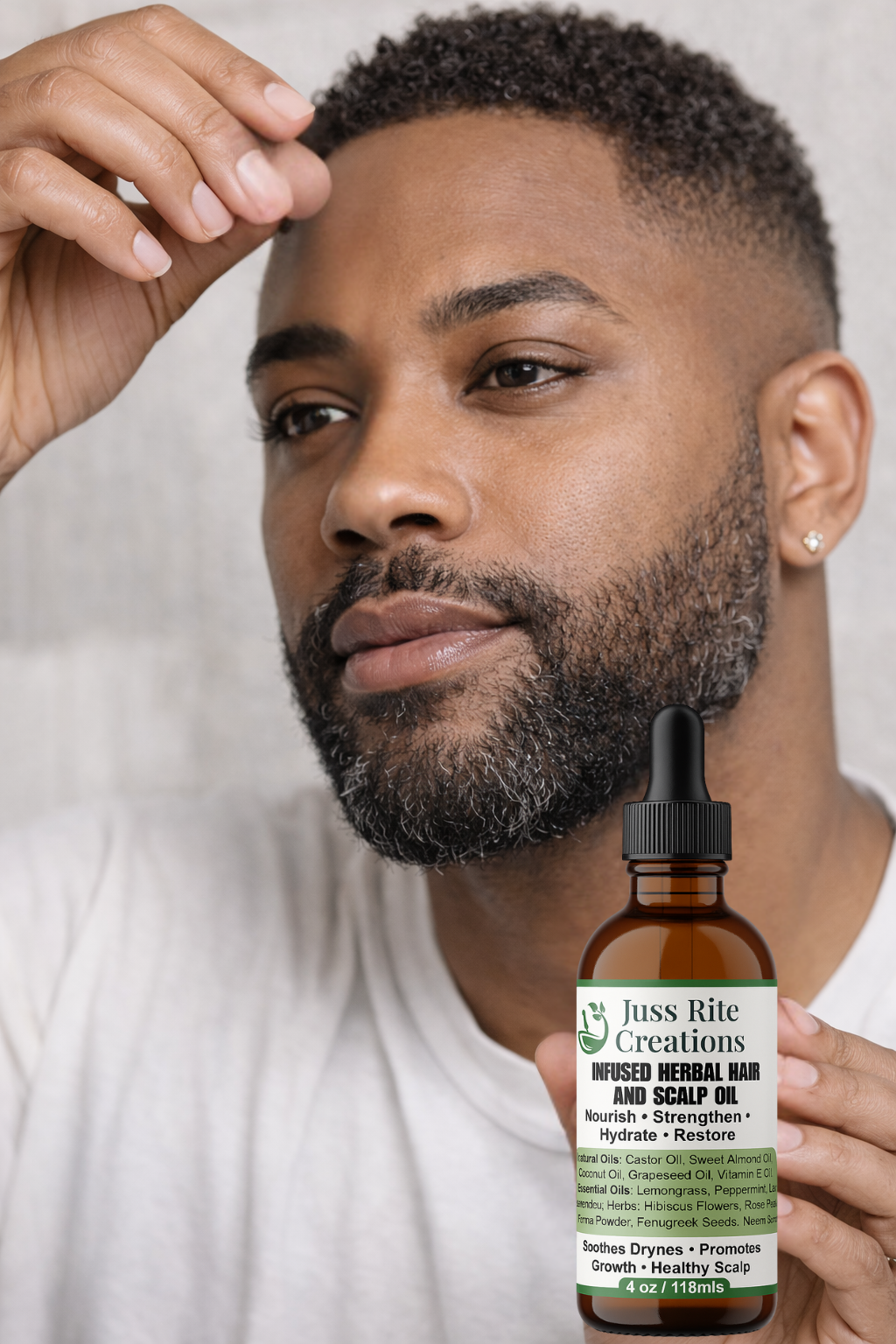 Man holding a bottle of 'Juss Rite Creations' hair and scalp oil with a white background