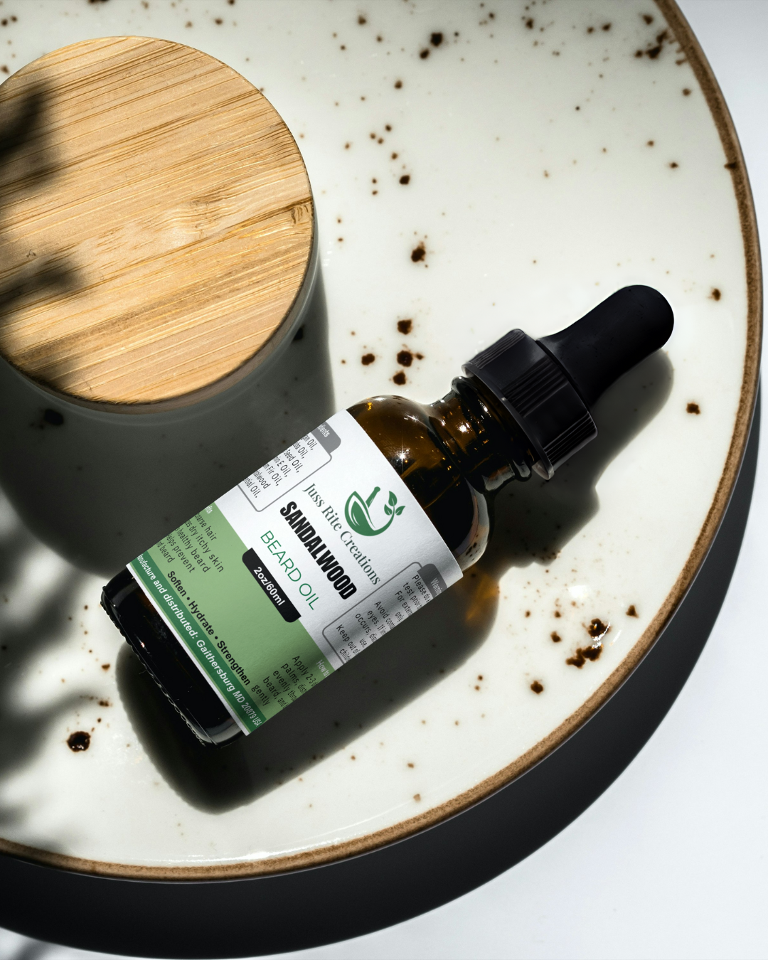 Bottle of Sandalwood essential oil with a dropper on a speckled ceramic plate.