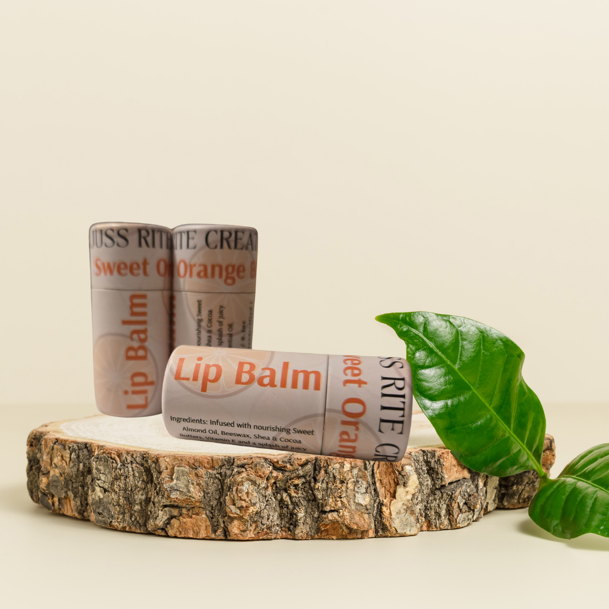 Two lip balms on a wooden block with green leaves on a beige background