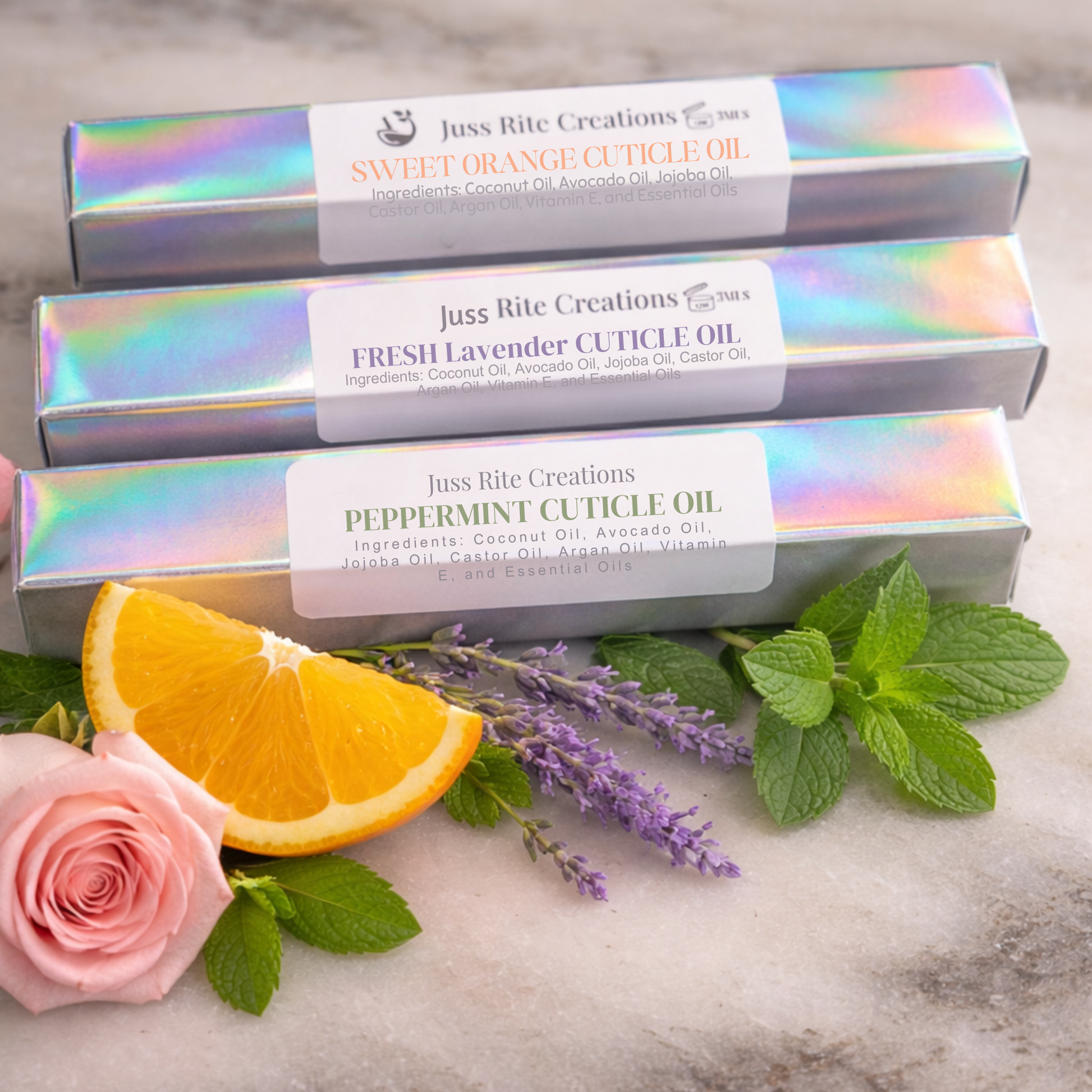Three boxes of Juss Rite Creations cuticle oil with orange, lavender, and mint on a marble surface.