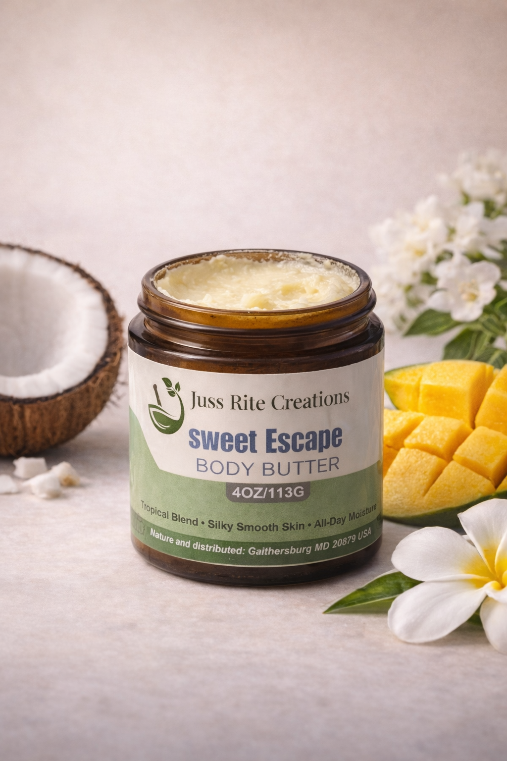 Jar of Juss Rite Creations sweet escape body butter with a coconut, mango, and flowers on a light background