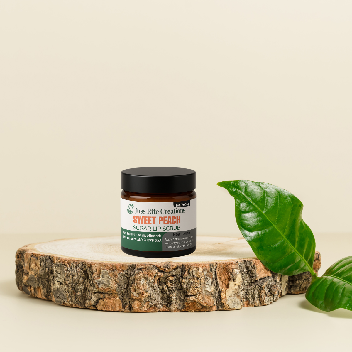 Jar of 'Sweet Peach' sugar lip scrub on a wooden platform with a green leaf on a beige background
